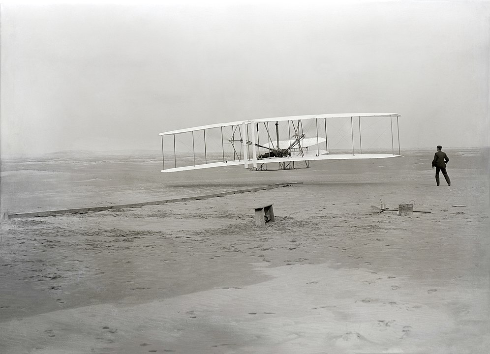 The first flight of the Wright Flyer, December 17, 1903, Orville piloting, Wilbur running at wingtip